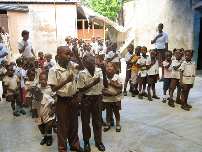 Haitian children looking upward as they raise the flag