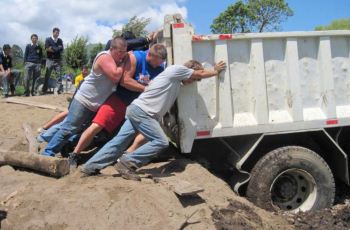 Young men pushing a large dump truck